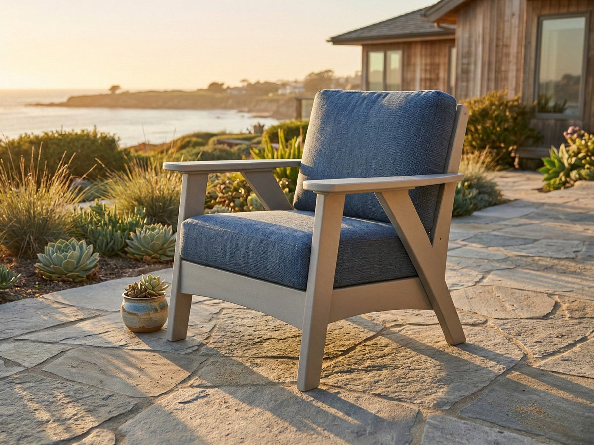 Light gray Regency deep-seating chair with blue cushions on a coastal stone patio